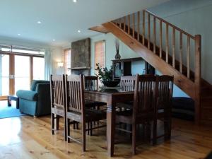 a dining room with a table with chairs and a staircase at Tikkandi in Merrijig
