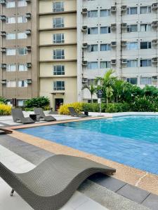 a swimming pool with chairs and a building at Pool View Cozy 1-Bedroom Unit Avida Aspira Tower 2 in Cagayan de Oro