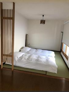 a small bedroom with a bed with white sheets at 小樽祝津山荘1号楼 in Otaru