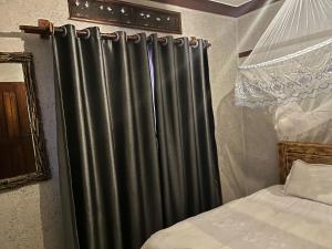 a black curtain in a bedroom next to a bed at Albertine Vacations Cottages in Kampala