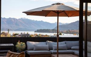 kanapę siedzącą pod parasolem na patio w obiekcie Great Lake View, Very Central, Modern Wanaka House, 3 En-suites w mieście Wanaka