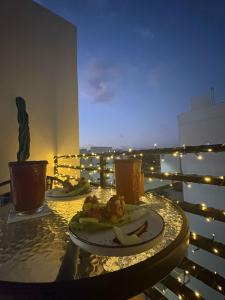 a table with a plate of food on a balcony with lights at Habitación privada en penthouse con roof top in Playa del Carmen