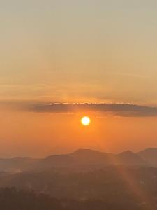 a sunset over mountains with the sun in the sky at The Space Garden Hotel Kandy in Nikawatawana