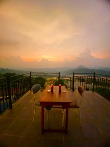 a table and chairs on a balcony with a sunset at The Space Garden Hotel Kandy in Nikawatawana