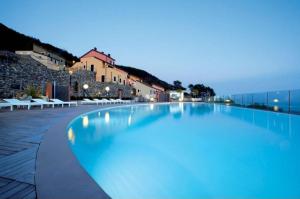 a large swimming pool at night with buildings in the background at Nido Dei Gabbiani in Magliolo