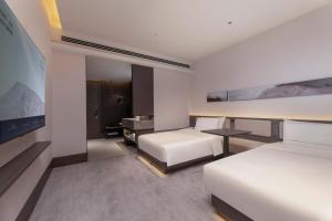 a hotel room with two beds and a desk at Atour Hotel Suzhou Gusu Dongzhong in Suzhou