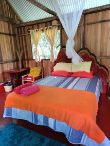 Bella Victoria Ecolodge في Santa María: غرفة نوم بسرير وبطانية برتقالية زرقاء