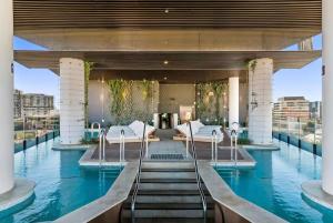 a hotel swimming pool with white beds and water at Magical Sunset SkyView BEST location in Brisbane in Brisbane
