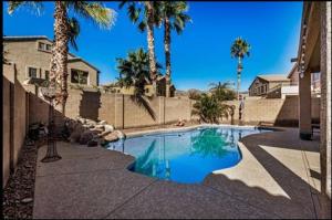 a swimming pool with palm trees in front of a house at The Reserve Large Home and Pool in Phoenix