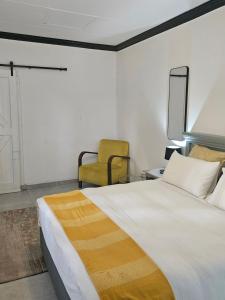Un dormitorio con una cama grande y una silla amarilla. en 43 Home, en Witbank