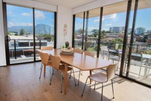 a dining room with a table and chairs and large windows at Kembla in Wollongong