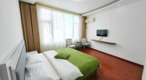 a bedroom with a green bed and a television at Mount Emei Fulin Hotel in Baoguosi