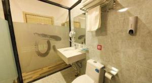 une salle de bain avec un lavabo, des toilettes et un miroir dans l'établissement PAI Hotel·Hami Yingbin Avenue Airport, à Hami