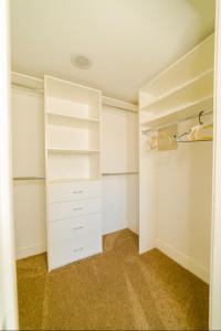 a walk in closet with white shelves and white cabinets at Western Santa Monica in Los Angeles