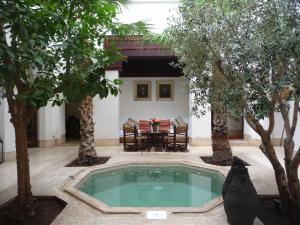 una piscina nel mezzo di un cortile alberato di Riad Matham a Marrakech