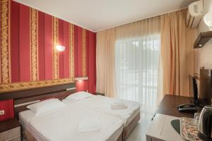 a bedroom with a bed with red walls and a window at Lotos Hotel in Balchik