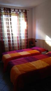 2 Betten in einem Zimmer mit Fenster in der Unterkunft B&B da Sguincio in Piateda