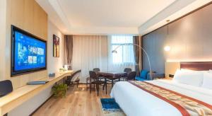 a hotel room with a large bed and a television at Gya Hotel Yangzhou Economic Development Zone Yangzijiang Nan Road Gaomin Temple in Yangzhou