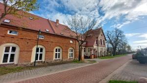 a brick building with a red roof on a street at Ferienwohnung Domaene Kermen in Kermen +47 photos