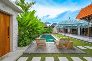 ein Haus mit einem Swimmingpool mit zwei Stühlen und einem Sonnenschirm in der Unterkunft Luxury 2BR Tropical Villa in Jimbaran, Bali in Jimbaran