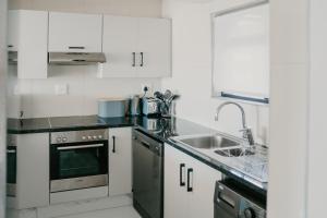 a kitchen with white cabinets and a sink at Gonubie Beachside Delight in East London