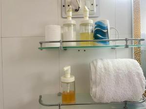 a glass shelf in a bathroom with bottles and a towel at Ganga Blessing Apartment in Rishīkesh +18 photos