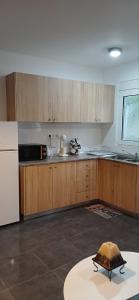 a kitchen with wooden cabinets and a white refrigerator at Tsampikas House in Faliraki