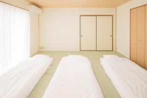 two beds in an empty room with a door at Itoshima inn 海 山 川が目の前でベッド8台 4LDK 一棟貸し in Itoshima
