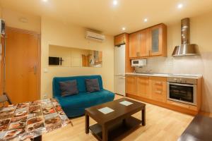 a living room with a blue couch and a kitchen at Apartment Bed&BCN Sant Andreu II in Barcelona