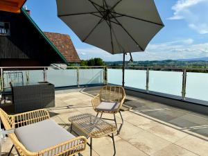 een terras met een tafel, stoelen en een parasol bij Mc Home Neues und sonniges Doppelhaus, Top 1 mit grosse Terrasse und E-Ladestation in Dobl bei Graz in Dobl
