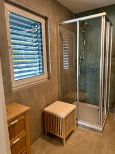 een badkamer met een douche, een bank en een kruk bij Mc Home Neues und sonniges Doppelhaus, Top 1 mit grosse Terrasse und E-Ladestation in Dobl bei Graz in Dobl +19 foto's