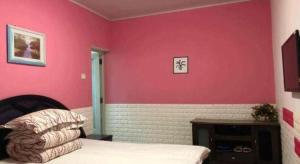 a bedroom with pink walls and a bed in a room at Lianyungang Jianyuan Hotel in Nancheng