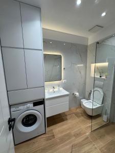 a bathroom with a washing machine and a toilet at Vitamine Luxury Apartments 2 in Sarandë +25 photos