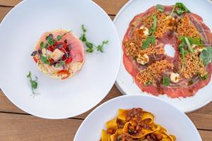 three plates of food on a wooden table at Sagredo Boutique Hotel & Spa in Ágios Fokás