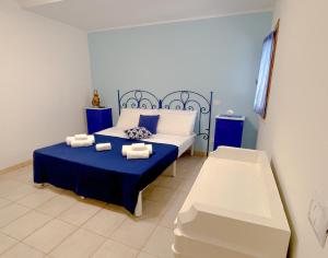 a bedroom with a blue and white bed and a bench at MARECHIARA Apartment - Independent ground-floor unit in central Nettuno with private patio, just 50 m from the sea and steps from the train station in Nettuno