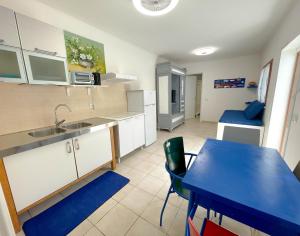 a kitchen with a table and a blue table and chairs at MARECHIARA Apartment - Independent ground-floor unit in central Nettuno with private patio, just 50 m from the sea and steps from the train station in Nettuno