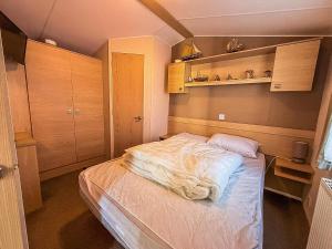 a small bedroom with a bed and wooden cabinets at Great 4 Berth Caravan With Wheelchair Access In Suffolk, Ref 68129Bs in Lowestoft +11 photos