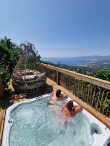 dwoje ludzi w wannie z hydromasażem na pokładzie w obiekcie Petit coin de paradis, vue panoramique mer &montagne, piscine privée... w mieście Calcatoggio