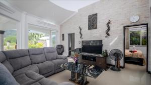a living room with a couch and a television at Luxurious & Quiet Pool Villa Orchid in Nai Yang Beach