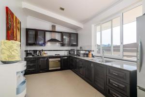 a kitchen with black cabinets and a large window at Luxurious & Quiet Pool Villa Orchid in Nai Yang Beach