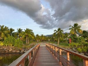a wooden bridge over a body of water with palm trees at Les Tainas bis in Faaa