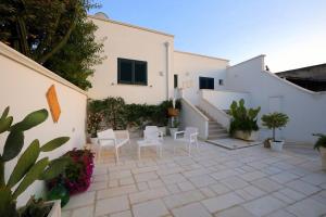a patio with white walls and white chairs and plants at B&B Sole Mare Vento in Maruggio