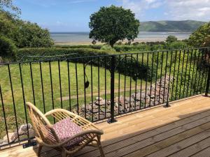 a chair on a deck with a view of the ocean at Worthy Barn in Minehead