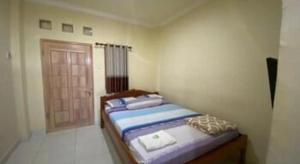 - une chambre avec 2 lits dans une pièce avec une porte dans l'établissement Capital O 93124 Lombok Northis Homestay, à Paloh