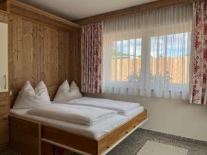 a bedroom with a bed with white sheets and a window at Boutique Apartment BERGLIEBE, ski in-out in Saalbach Hinterglemm +46 photos