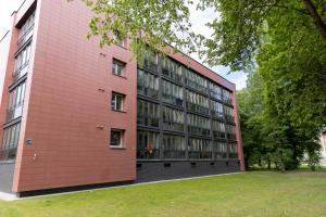 un grand bâtiment en briques rouges avec une cour gazonnée dans l'établissement Apartamentai Akvilė, à Šilutė