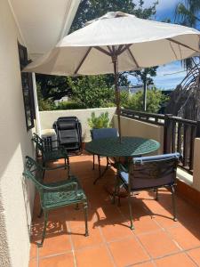 a patio with a table and chairs and an umbrella at Bakoven Cottage in Cape Town