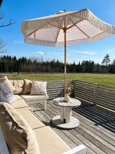 a patio with a table and an umbrella on a deck at Charming Family Villa in Ulricehamn