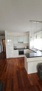 a kitchen with white cabinets and a wooden floor at Apartament 1000-lecia in Władysławowo