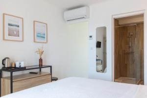 a white bedroom with a bed and a bathroom at HOTEL CAMPOMORO in Belvédère-Campomoro